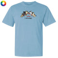 A light blue short-sleeve crewneck t-shirt featuring a cartoon graphic of several dogs eating red hearts with the text 'I call bullshit' underneath. A small multicolor color wheel icon is visible in the top-left corner.