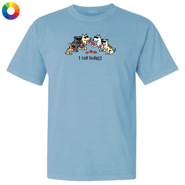 A light blue short-sleeve crewneck t-shirt featuring a cartoon graphic of several dogs eating red hearts with the text 'I call bullshit' underneath. A small multicolor color wheel icon is visible in the top-left corner.