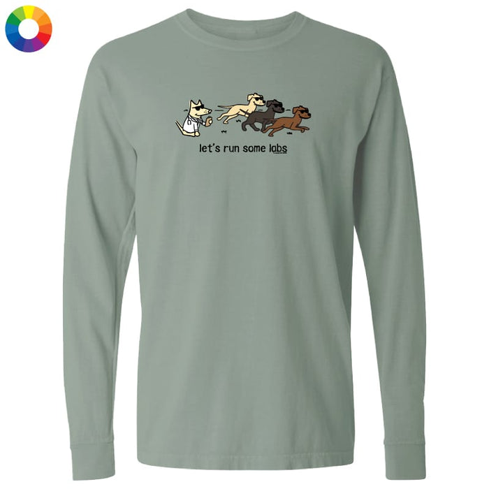 A sage green long-sleeve t-shirt with a graphic of a cat chasing three dogs and the text 'let's run some k9s' printed on the chest, displayed on a clean white background.
