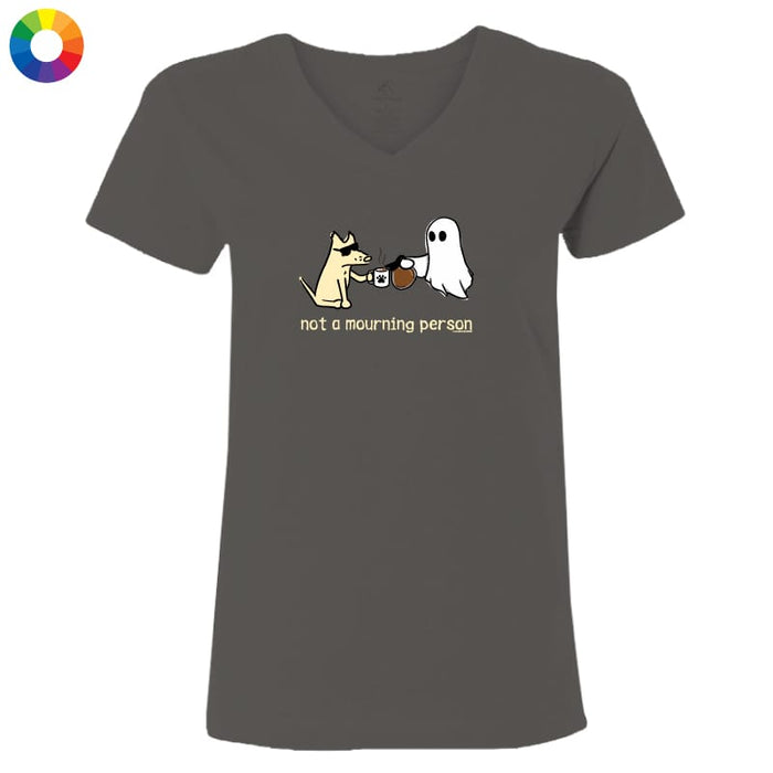A dark gray v-neck t-shirt with a cartoon graphic of a dog and a ghost sharing a mug, with the text 'not a mourning person' printed below. The t-shirt is displayed on a clean white background, with a small multicolor color wheel icon in the top-left corner.